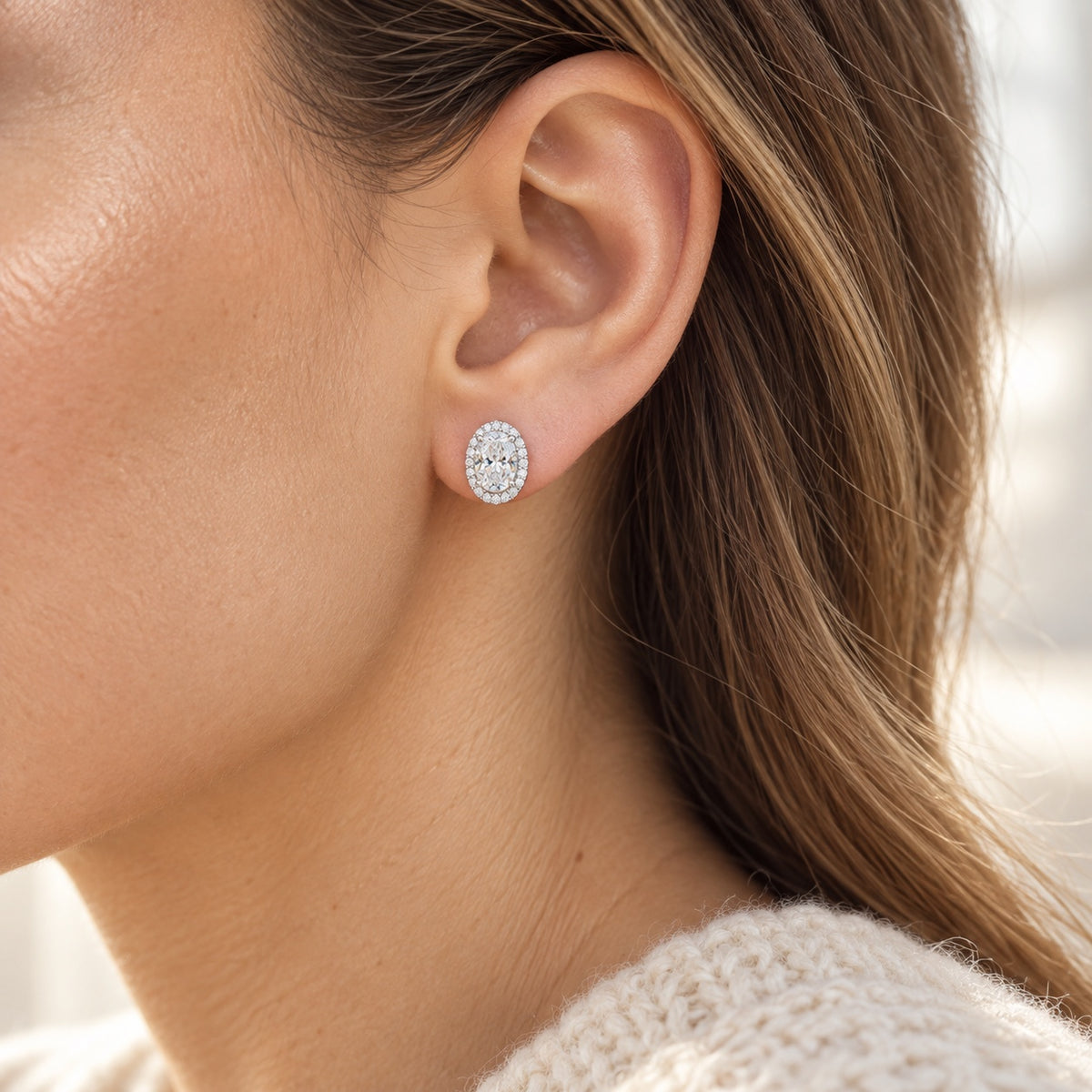 The Oval Halo Moissanite Studs worn by a model in natural daylight