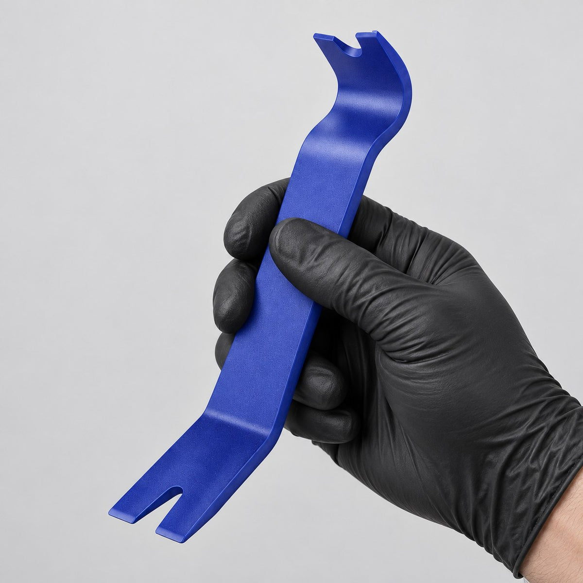 Trim removal tool held in a gloved hand to show its size