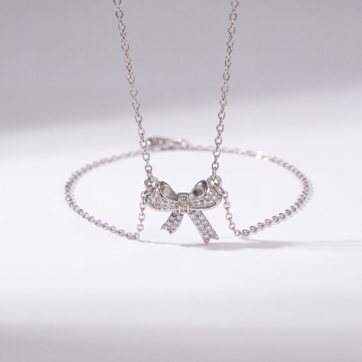 The Bow Necklace by JUSMIR, bow pendant necklace with clear stones, studio product photo