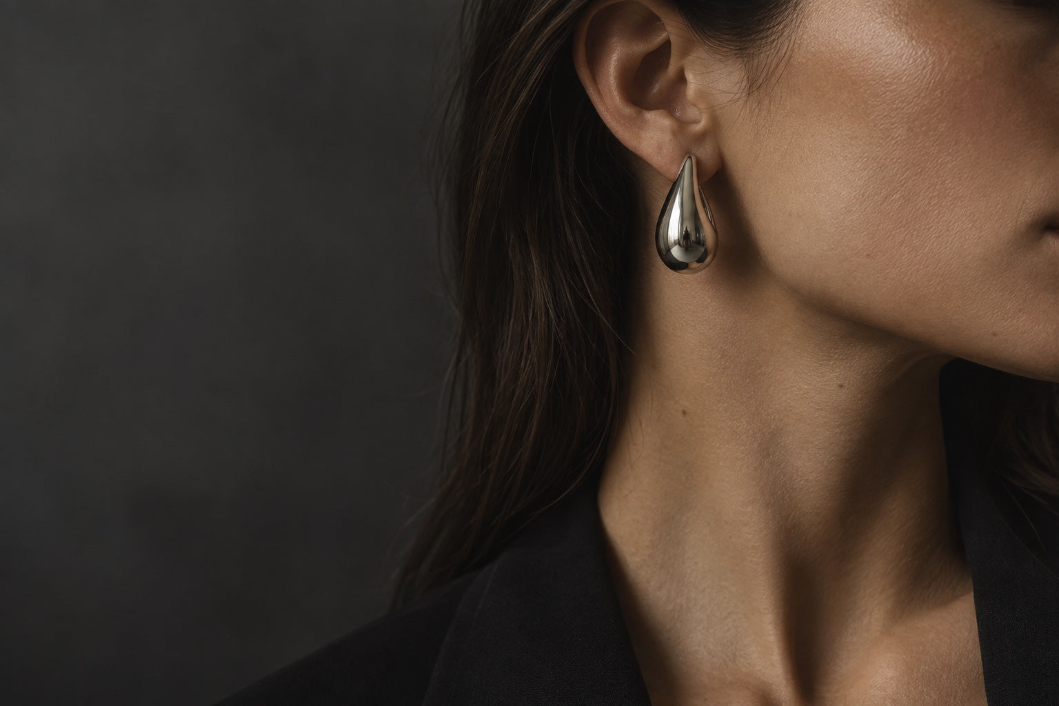 Editorial close-up of a sculptural silver-tone earring